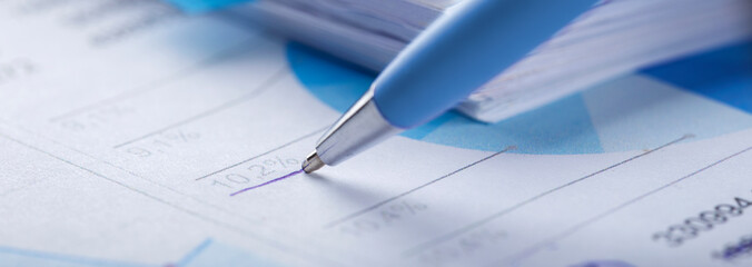 Accounting document with pen, money, coins and checking financial chart. Concept of banking, financial report and financial audit.