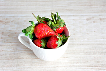 heap of strawberries in white cup isolated on beige background