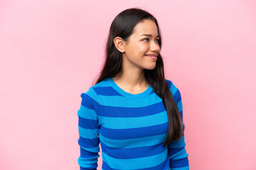 Young Colombian woman isolated on pink background looking to the side
