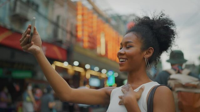 Beautiful Young black woman travel at city alone. She using mobile to selfie or videocall at city.