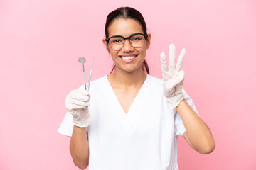 Dentist Colombian woman isolated on pink background happy and counting three with fingers