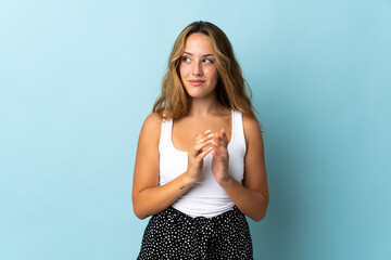 Young blonde woman isolated on blue background scheming something