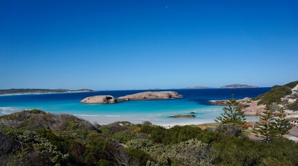 Einsamer weißer Sandstrand hinter grünen Büschen mit zwei Steininseln