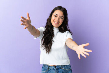 Young caucasian woman isolated on purple background presenting and inviting to come with hand