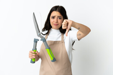 Young caucasian woman holding a plant isolated on white background showing thumb down with negative expression