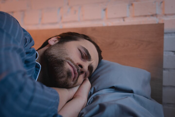 Fototapeta premium Young man with closed eyes lying on bed
