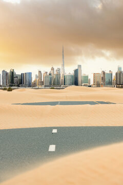 Stunning view of a road covered by sand dunes with the Dubai Skyline in the distance. Dubai, United Arab Emirates..