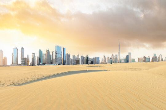 Stunning view of a road covered by sand dunes with the Dubai Skyline in the distance. Dubai, United Arab Emirates..