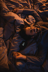 Plakat Top view of man in pajama yawning near alarm clock on bed at night