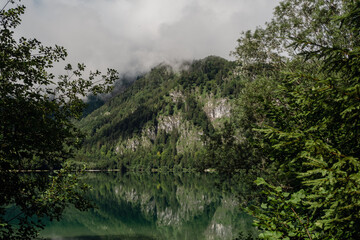 Fototapeta na wymiar foggy morning above the lake in the mountains with crystal clear water like a mirror