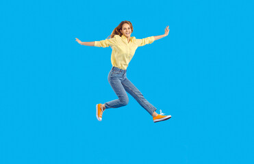Fototapeta na wymiar Full length body size view of nice attractive lovely glad cheerful wavy-haired woman raising hands screaming laughing wearing yellow shirt jeans sneakers over blue background. People emotions concept
