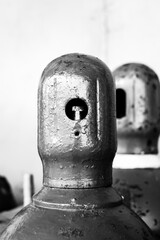 Compressed gas cylinders being stored vertically secured by a metal chain and a metal cap.