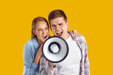 Screaming in megaphone. Young expressive and crazy couple using megaphone to address you,...