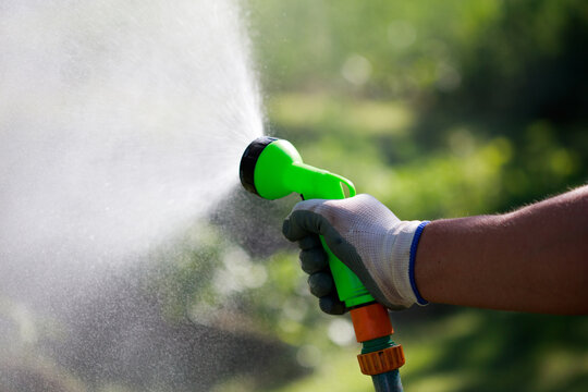 Water spray gun with hose in a man's hand. Watering the lawn using the hose concept.