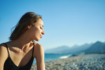 Fototapeta na wymiar Outdoor portrait beautiful summer girl enjoying weekend at beach with mountains by the sea
