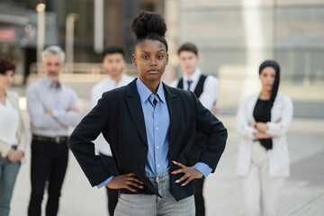 portrait of female african american businesswoman, and her team of workers outside - business concept -