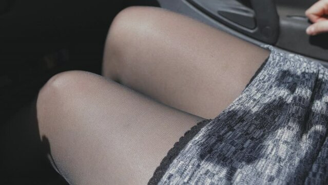 women's legs in black stockings, a woman sitting in a car, a slender figure