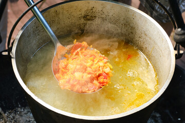 Cooking fish soup or uha on a fire. Delicious fish broth with vegetables. Shallow depth of field.