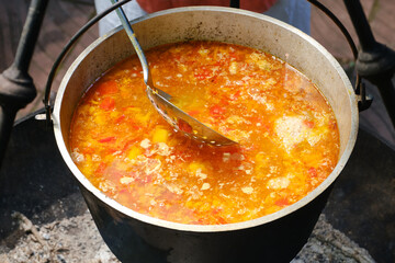 Cooking fish soup or uha on a fire. Cast iron cauldron with boiling fish broth. Shallow depth of field.