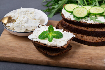 Home made bread on a wooden cutting board with curd cheese and ricotta