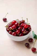 Bowl of fresh ripe cherries on pink background. Copy space for text. Selective focus.