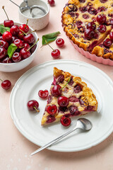 Slice of clafoutis with cherry on white plate. Traditional homemade french cherry pie. Selective focus.
