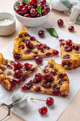 Slices of clafoutis with cherry on baking paper. Traditional homemade french cherry pie. Selective focus.