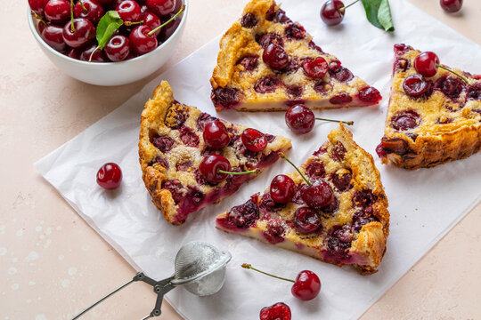 Slices of clafoutis with cherry on baking paper. Traditional homemade french cherry pie. Selective focus.