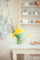 Bouquet of yellow flowers of daffodils in a glass vase on a wooden table in a bright room