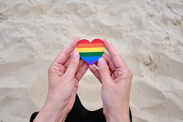 Rainbow heart from paper in woman hands. LGBT flag. LGBTQIA Pride Month in June. Lesbian Gay Bisexual Transgender. Gender equality. Human rights and tolerance. Rainbow flag 
