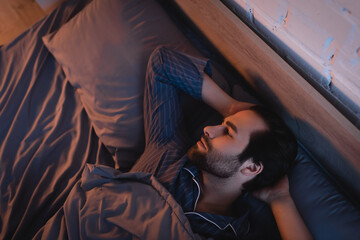 Side view of man with sleep disorder lying on bed at home