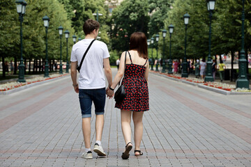 Young couple walking on a street holding hands. Life in summer city, happy lovers