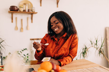 Beautiful young woman eating yogurt in the kitchen in the morning. Healthy food. Portrait shot