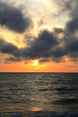 Naklejka na ściany i meble dark rainy cumulous clouds and epic sunset on the beach