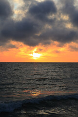 dark rainy cumulous clouds and epic sunset on the beach