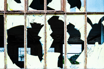 frame within a frame broken glass window panes create abstract pattern in abandoned industrial...