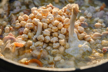 Cast iron cauldron with pilaf on a fire. Garlic bulb and chickpeas. Shallow depth of field