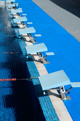 Numbered diving boards along the edge of a competitive swimming pool with swimming lanes