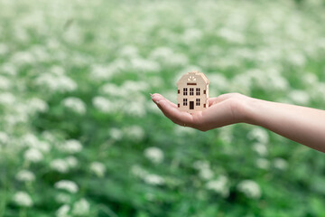 hand holds a small wooden house in the palm of your hand, buying, selling and building houses, real estate agent