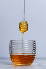 Honey dripping from the honey pot. Diving spoon of honey - Close up.