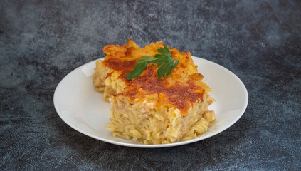 Pasta casserole bechamel sauce topped with melted mozzarella cheese and served in a white baking dish on a table (Turkish name; firinda makarna or firin makarna)