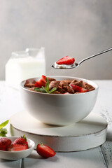 Healthy breakfast. Milk yogurt with pads, fresh strawberries and mint in a white bowl on a white wooden table. Rustic. Background image, copy space
