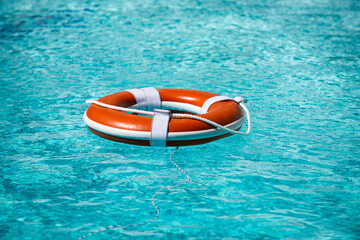 Life buoy in blue swimming pool. Lifebuoy pool ring float on blue water.