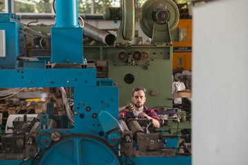 The young craftsman works on a large printing machine in the company.