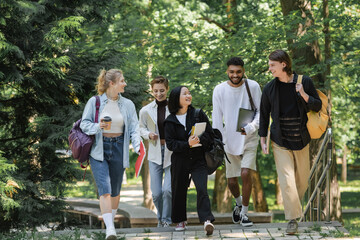 Happy asian student walking near multiethnic friends in park.