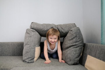 funny European child playing with pillows on couch