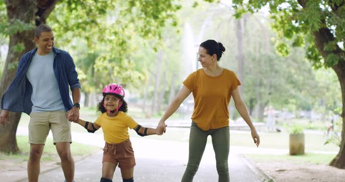 Family with cute adopted girl learning to roller skate with her parents. Young adoptive couple teaching foster daughter how to rollerblade outside in the park. Mother, father and their adorable kid