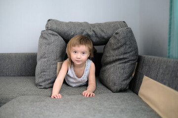 Fototapeta premium funny European child playing with pillows on couch