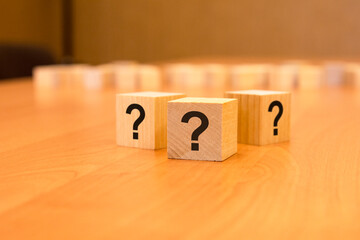 three cubes with question mark on wooden background. space for text