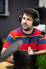 Portrait of young caucasian male with headphones in recording studio. Radio presenter, commentator, podcaster, live broadcast.